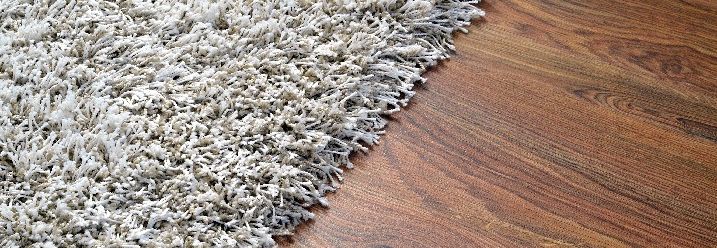 Heller Teppich auf dunklem Holzboden